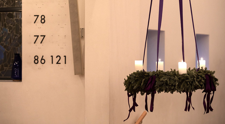 Adventskrans med tændte stearinlys.