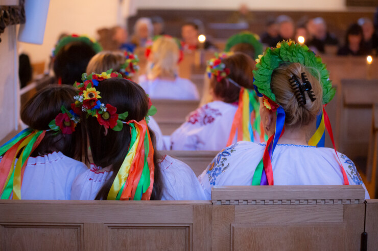 Ukrainere med ukrainsk påklædning sidder til gudstjeneste
