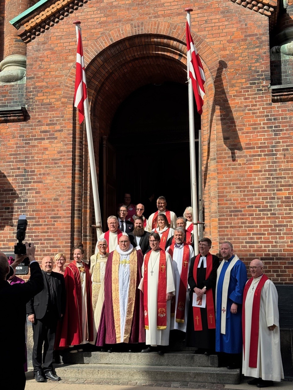 Gruppebillede med den nye metodistbiskop foran kirken